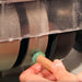close up of hands holding a green gemstone on a wet spinning, grinding diamond wheel on the cabking 6 cabbing machine with water dripping from stone