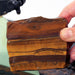 close up of hands holding a slice of tigers eye stone with hi-tech 10 inch slab saw