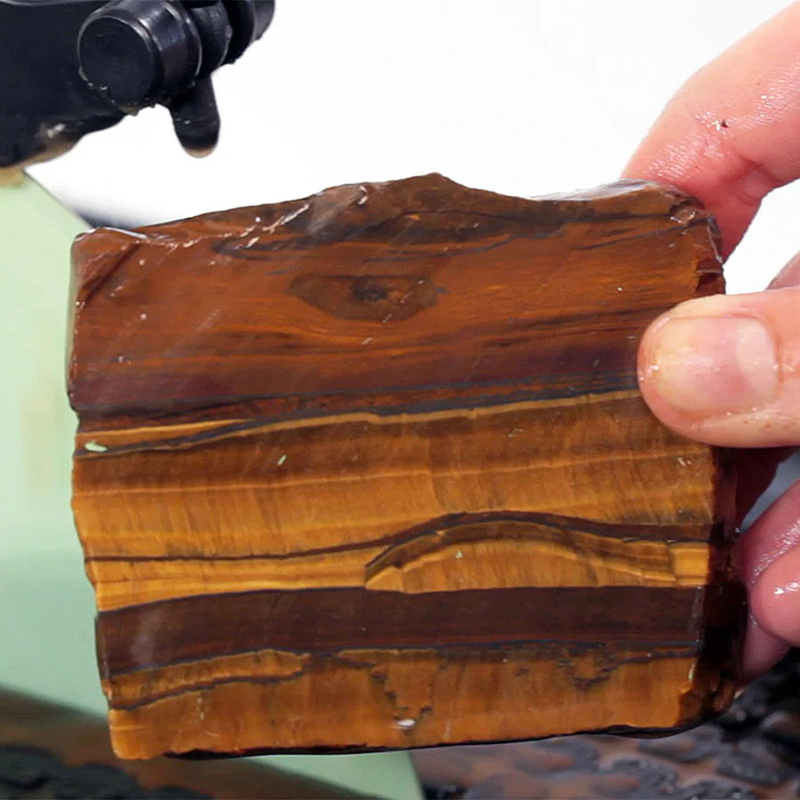 close up of hands holding a slice of tigers eye stone with hi-tech 10 inch slab saw