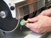 hand holding a cabochon on a dop stick with dop wax polishing a gemstone on the 1st grinding wheel of the cabkiing 8" cabbing machine