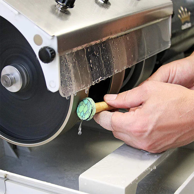 hand holding a cabochon on a dop stick with dop wax polishing a gemstone on the 1st grinding wheel of the cabkiing 8" cabbing machine