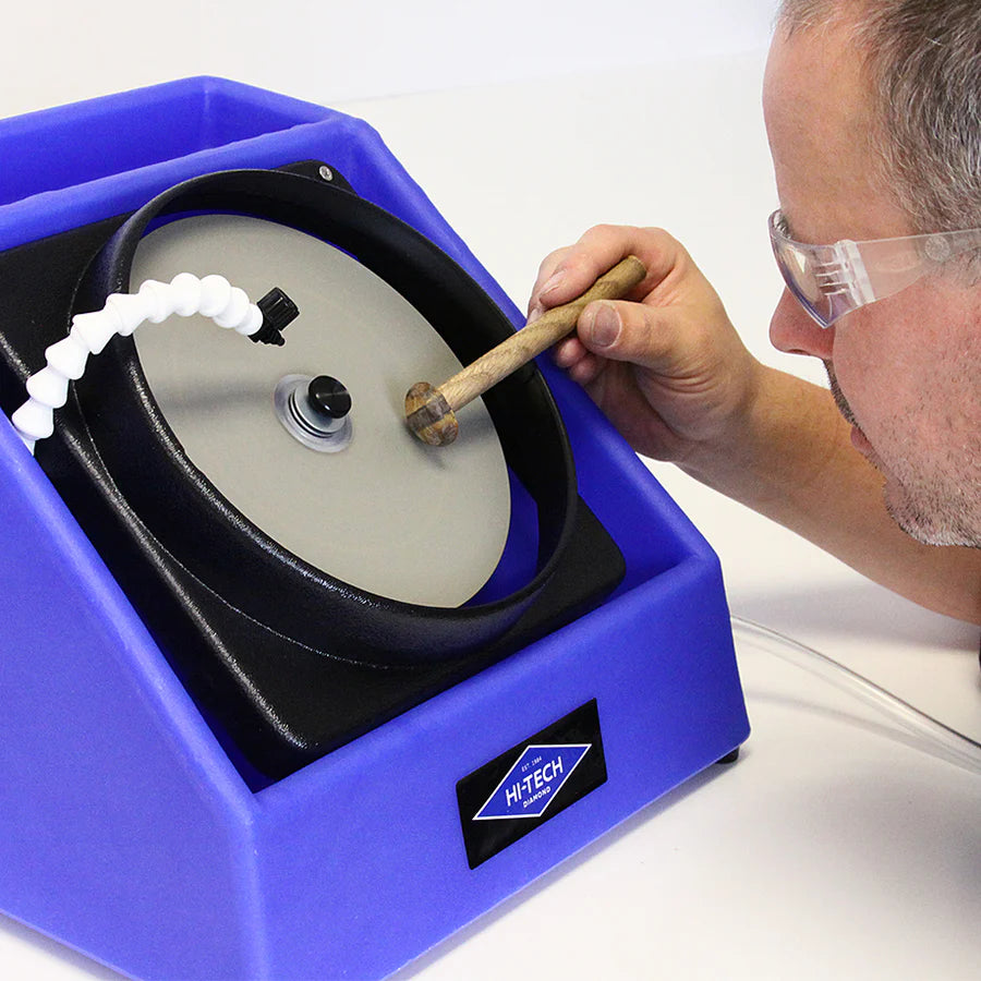 close up of a person holding a cabochon to the hi tech diamond flat lap as it is spinning using a dop stick and dop wax to polish a gemstone
